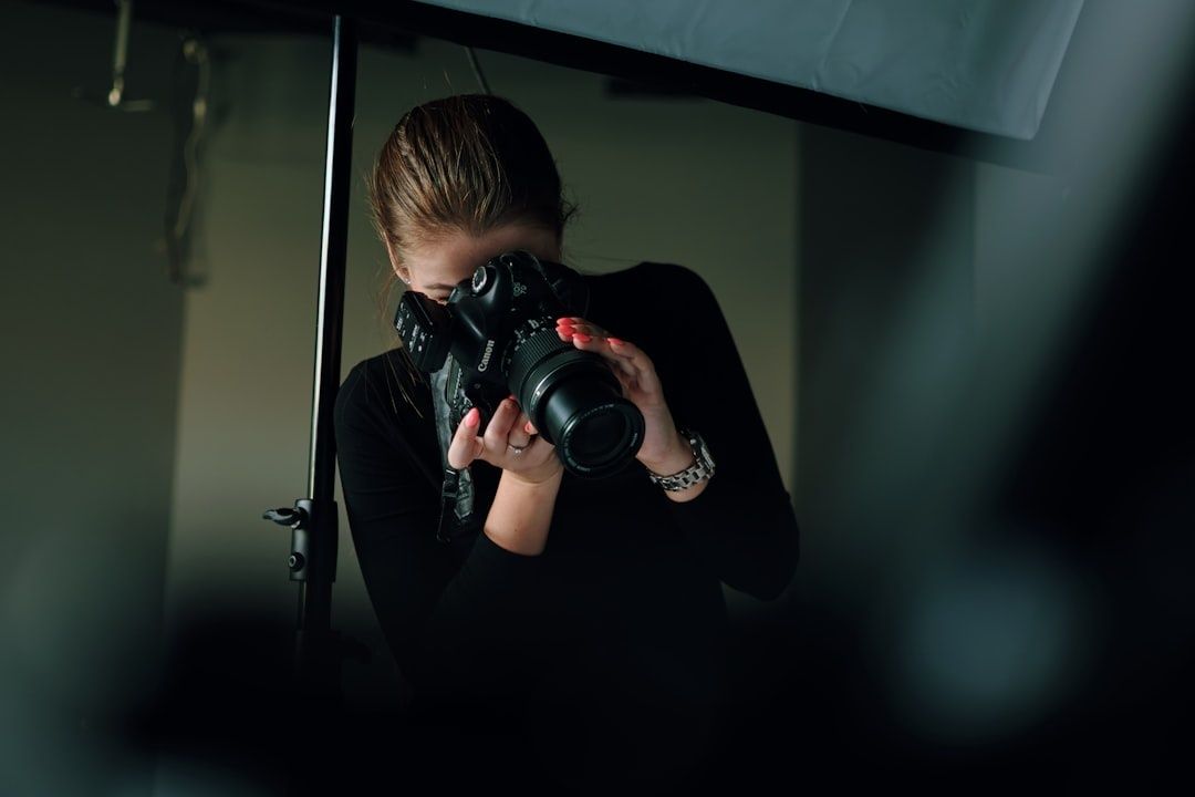 Fotograf håller en Canon-kamera och fotograferar genom en sökare