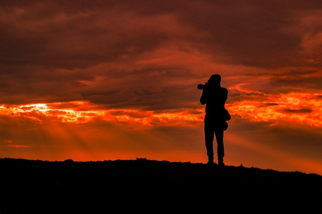 Fotograf i siluett mot en intensivt orange solnedgångshimmel